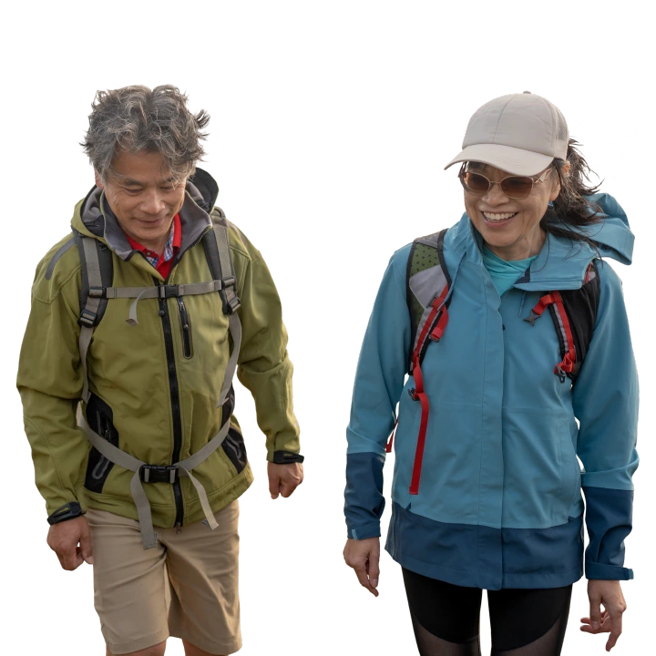 middle-aged couple in rain jackets walking on the beach